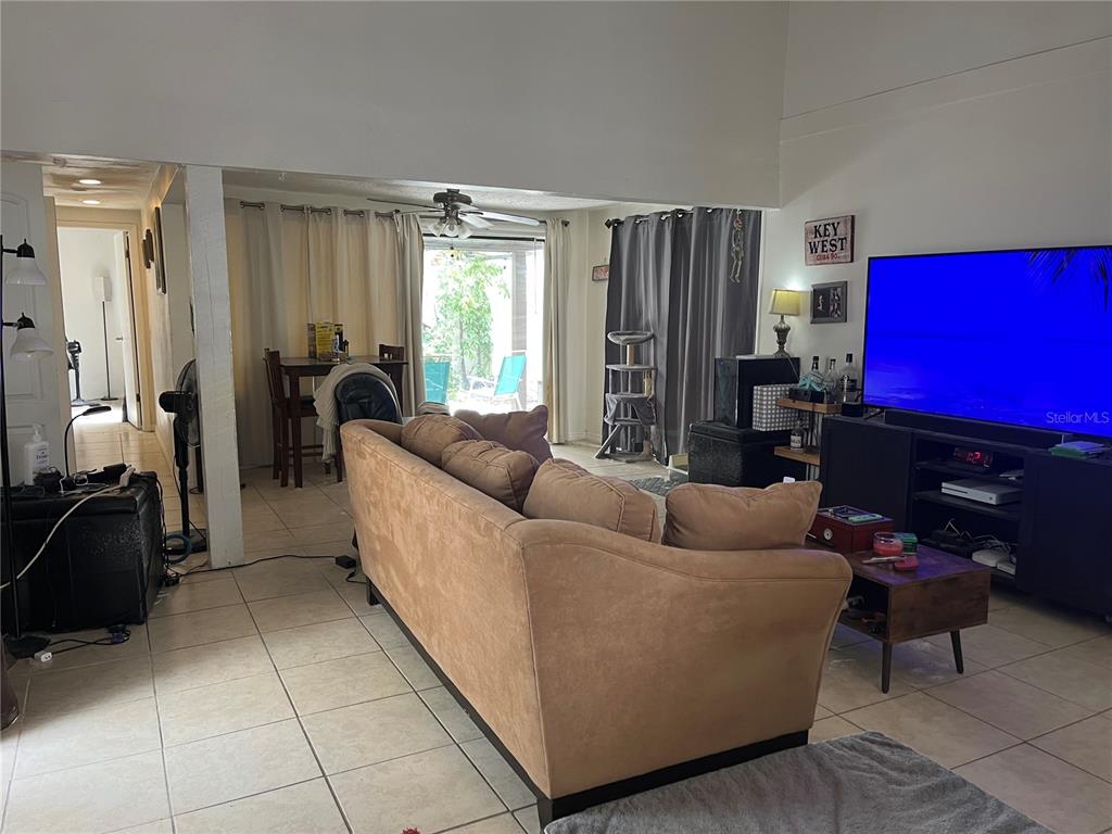 A living room with a tan sofa, television, and dining area visible through an open doorway — 12506 FOX CROFT LANE, HUDSON, FL