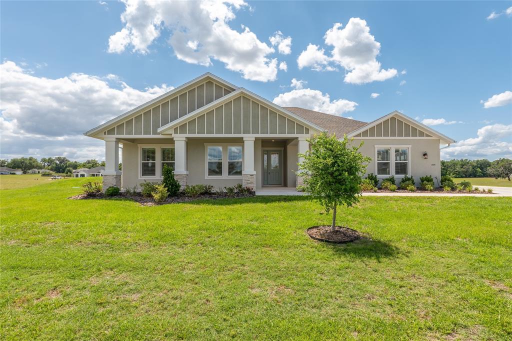 A single-story house with light-colored stucco, board-and-batten siding, and a covered front porch — 1929 NW 85TH LOOP, OCALA, FL