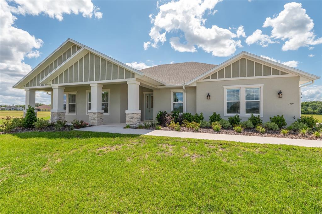 A single-story house with a covered porch, stone pillars, and light-colored siding under a sky — 1929 NW 85TH LOOP, OCALA, FL