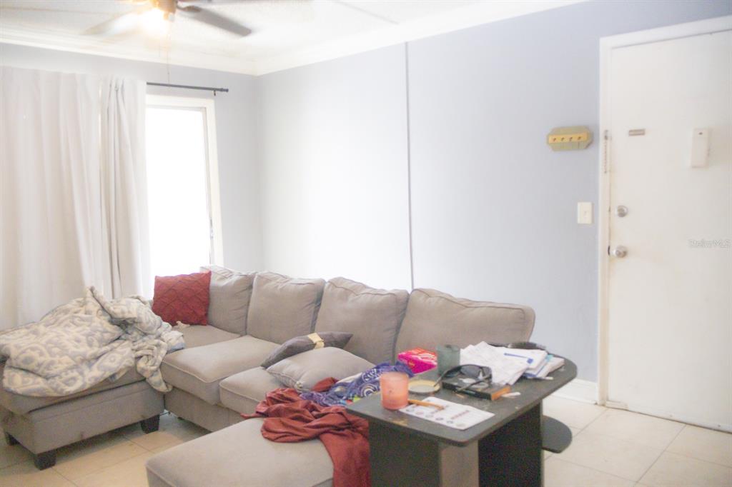 A living room features a large gray sectional sofa, tile flooring, and a white door — 924 LAKE DESTINY ROAD UNIT D, ALTAMONTE SPRINGS, FL