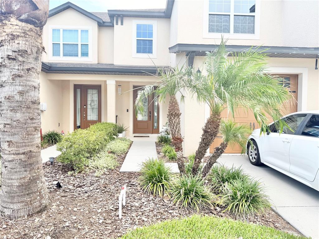 A two-story townhouse exterior features a brown front door, a palm tree, and a driveway — 11287 CAY SPRUCE WAY, SAN ANTONIO, FL