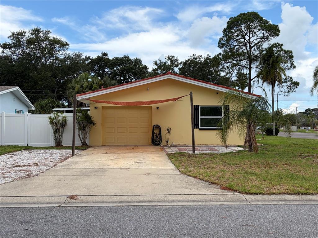 A yellow single-story house with a garage, a driveway, and a shade sail — 623 PALM BOULEVARD, DUNEDIN, FL