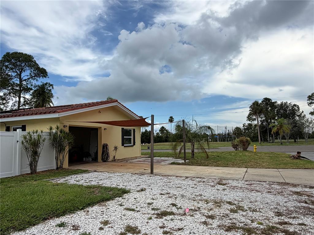 A yellow house with a garage, a shade sail, and a white gravel driveway — 623 PALM BOULEVARD, DUNEDIN, FL