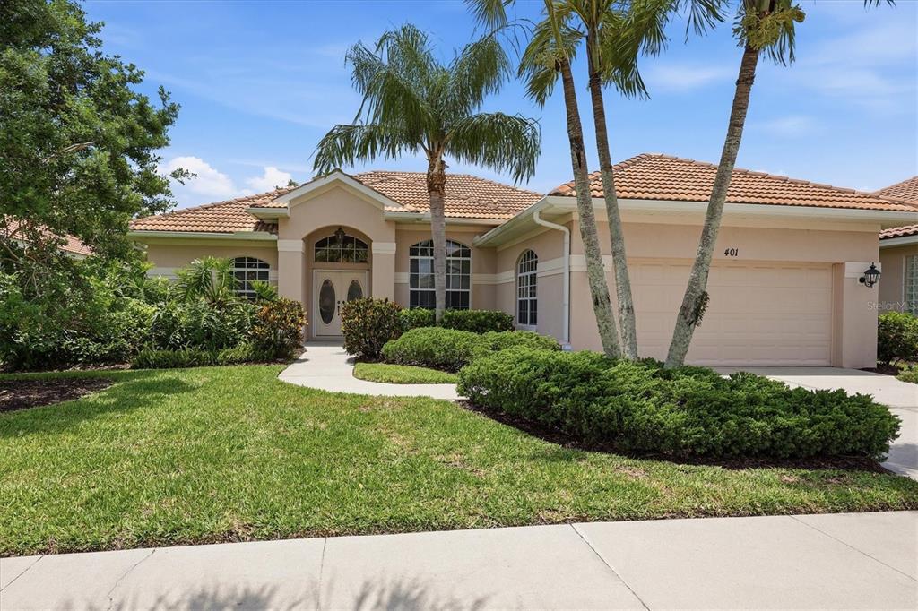 A single-story house with a beige stucco exterior, tile roof, and a two-car garage — 401 MARSH CREEK ROAD, VENICE, FL