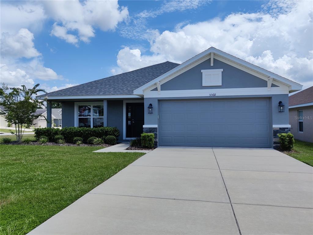 A single-story house with a gray exterior, a two-car garage, and a concrete driveway — 5568 OCEAN BREEZE DRIVE, SPRING HILL, FL