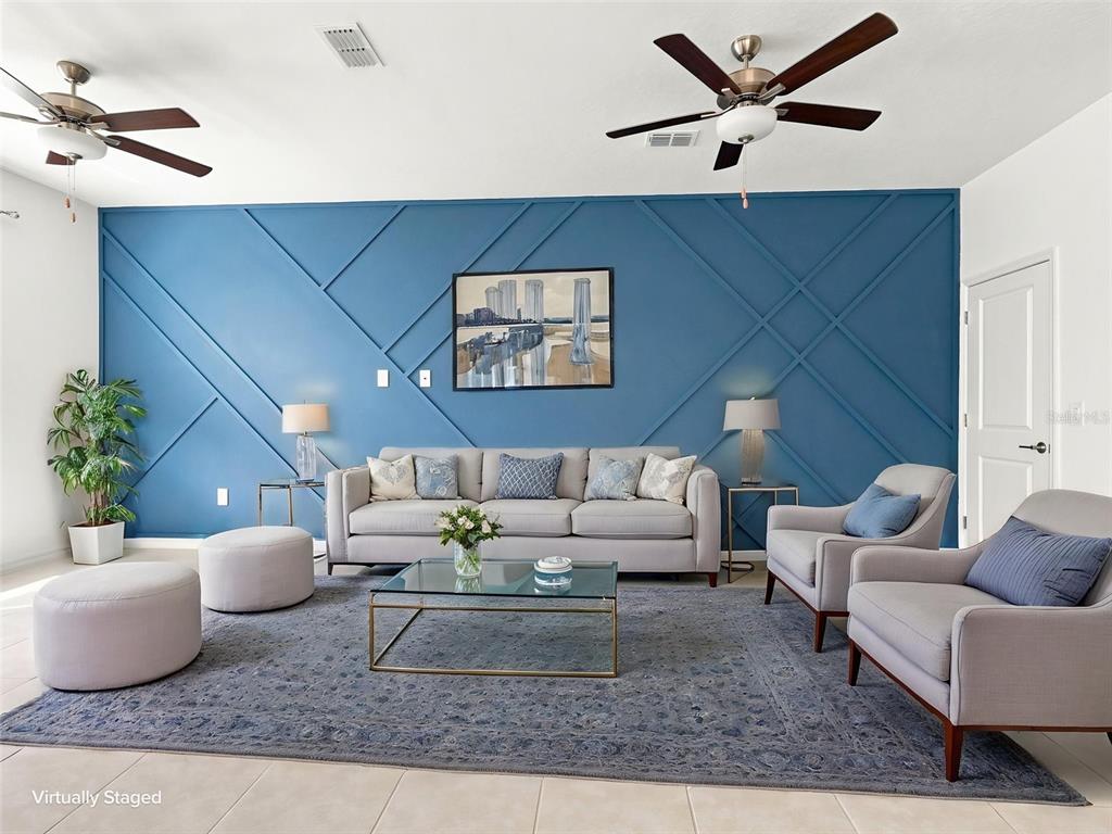 A living room features a blue accent wall with geometric molding and light gray furniture — 10317 TRUMPET HONEYSUCKLE WAY, SAN ANTONIO, FL