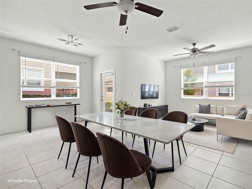 This open-concept living and dining area features white tile floors, ceiling fans, and neutral walls — 10317 TRUMPET HONEYSUCKLE WAY, SAN ANTONIO, FL