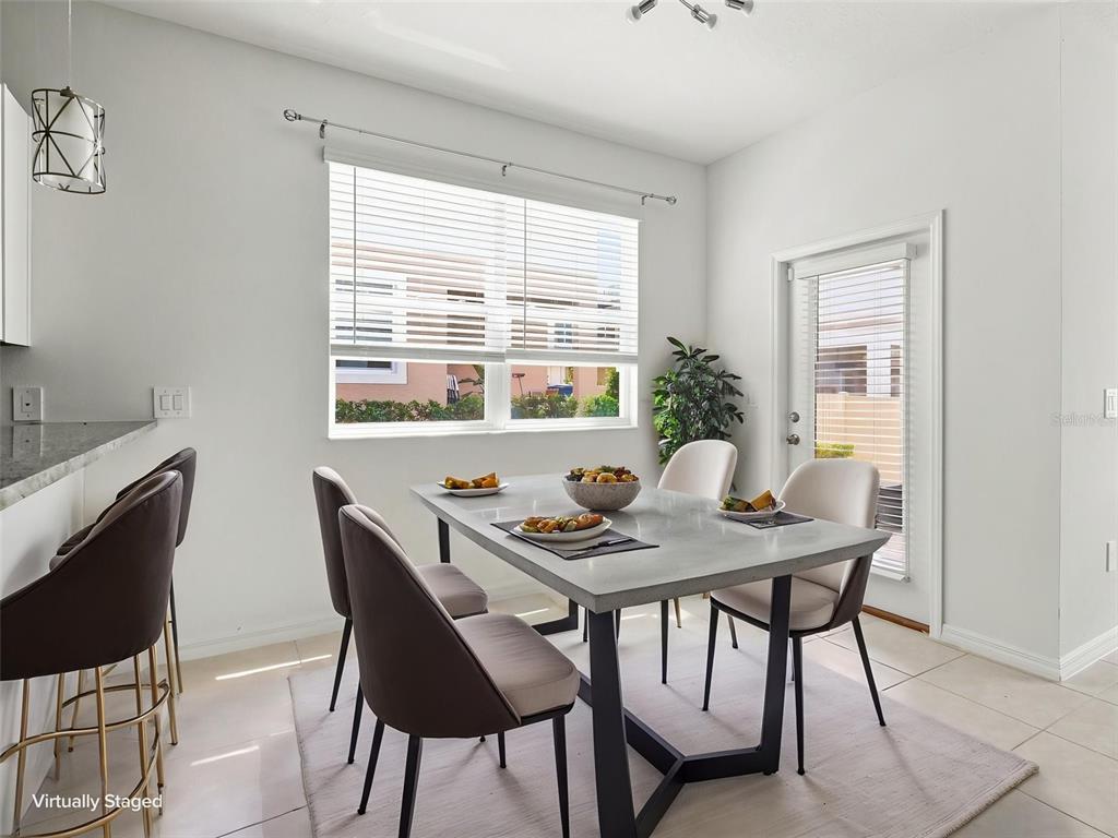 A dining area features a concrete table with four chairs, a window, and a glass door — 10317 TRUMPET HONEYSUCKLE WAY, SAN ANTONIO, FL