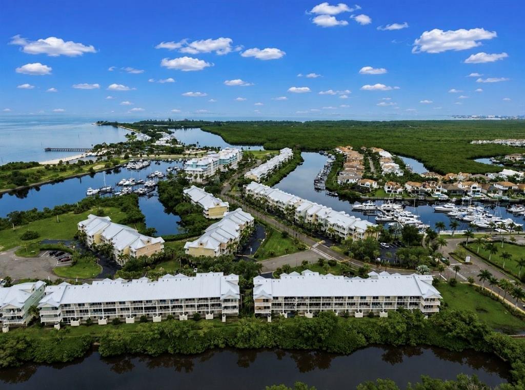 Aerial view of a waterfront residential complex with multiple buildings, boat slips, and surrounding mangroves — 3228 MANGROVE POINT DRIVE, RUSKIN, FL