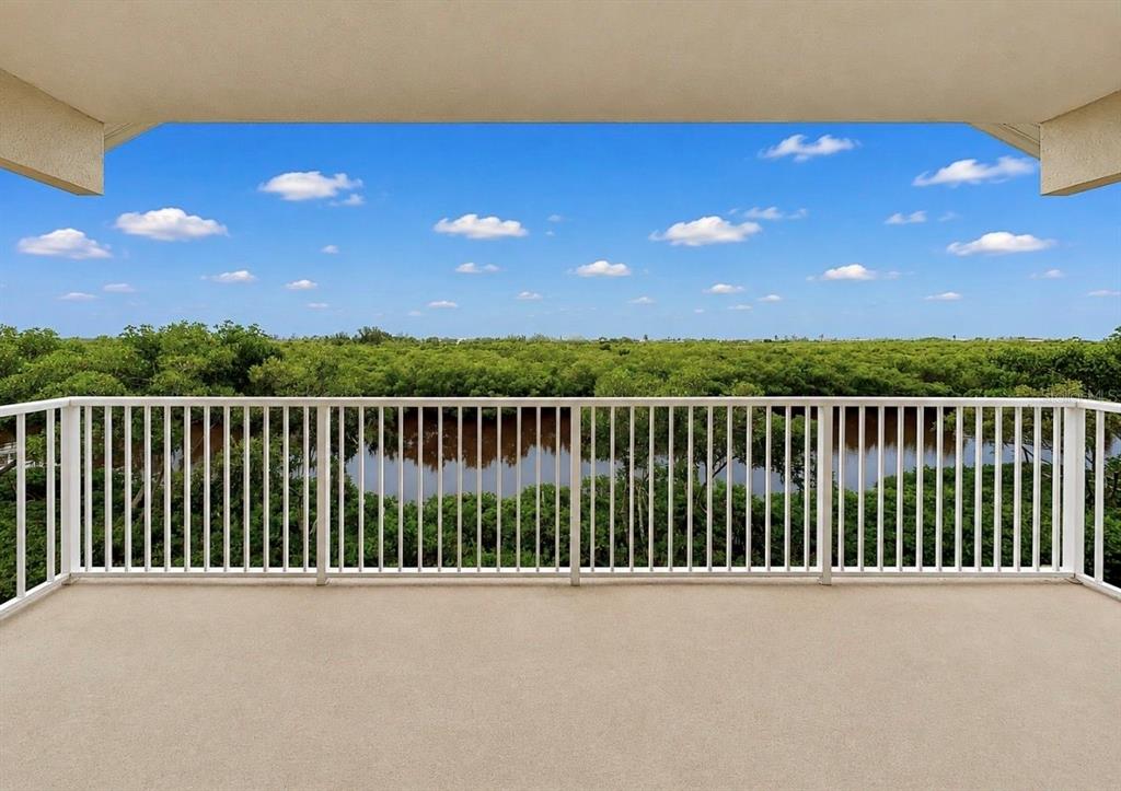 A balcony with a white railing overlooks a body of water and dense green trees — 3228 MANGROVE POINT DRIVE, RUSKIN, FL
