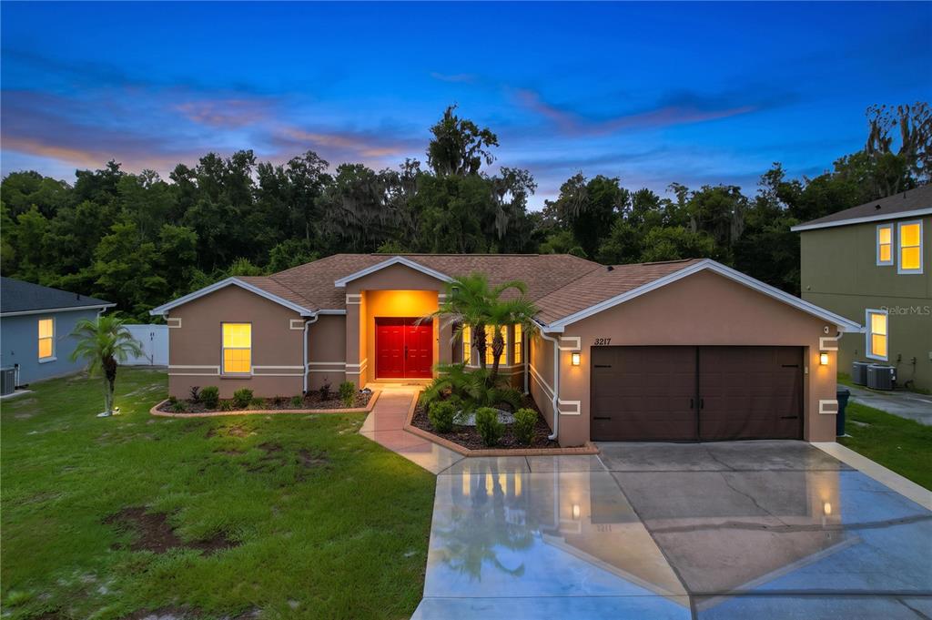 A living room with a sectional sofa, wood-look tile flooring, and an open dining area — 3217 ENCLAVE BOULEVARD, MULBERRY, FL