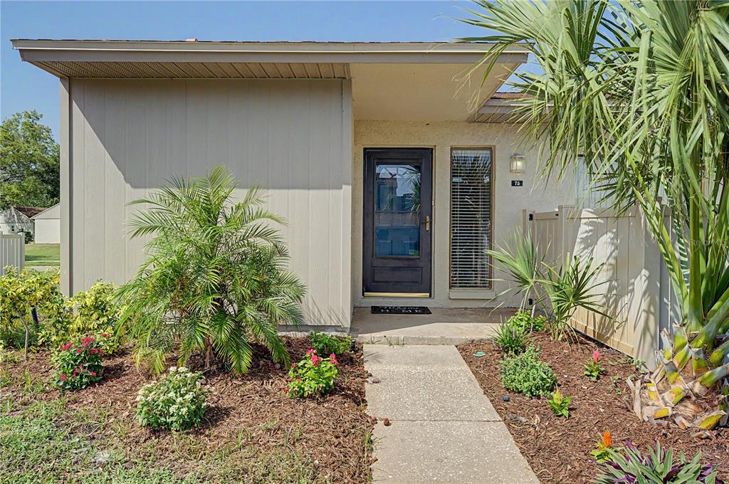 A single-story home exterior features a concrete walkway leading to a dark front door — 75 POOLE PLACE, OLDSMAR, FL