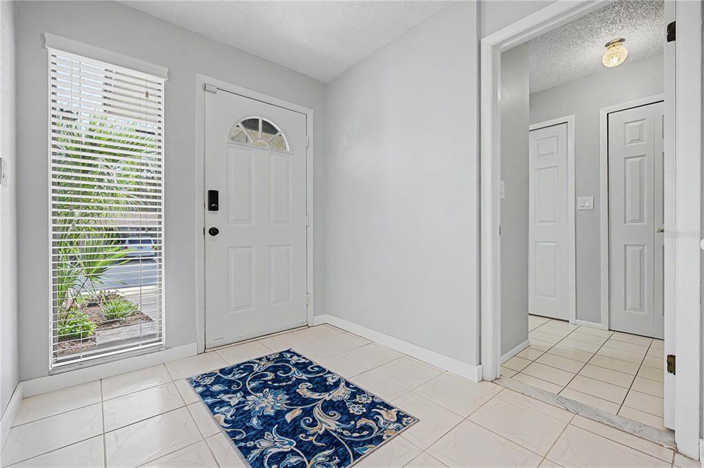 An entryway features light-colored tile flooring, a white front door, and a blue patterned rug — 75 POOLE PLACE, OLDSMAR, FL