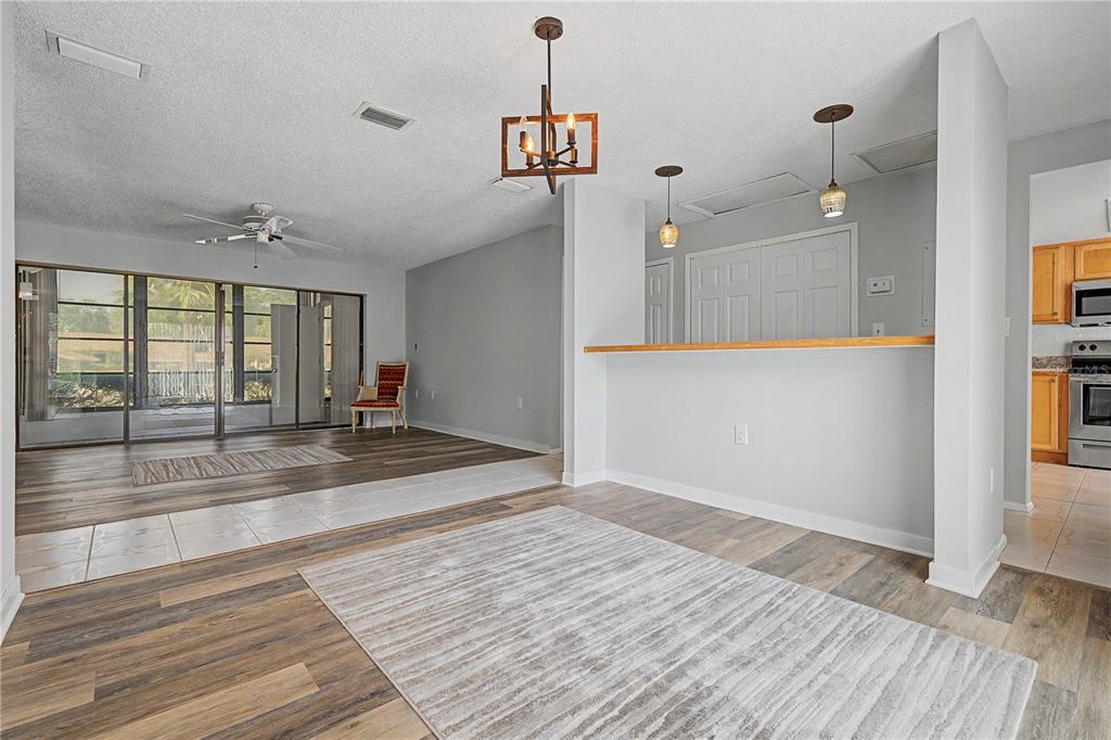 A living and dining area features wood-look flooring, a breakfast bar, and a sliding glass door — 75 POOLE PLACE, OLDSMAR, FL
