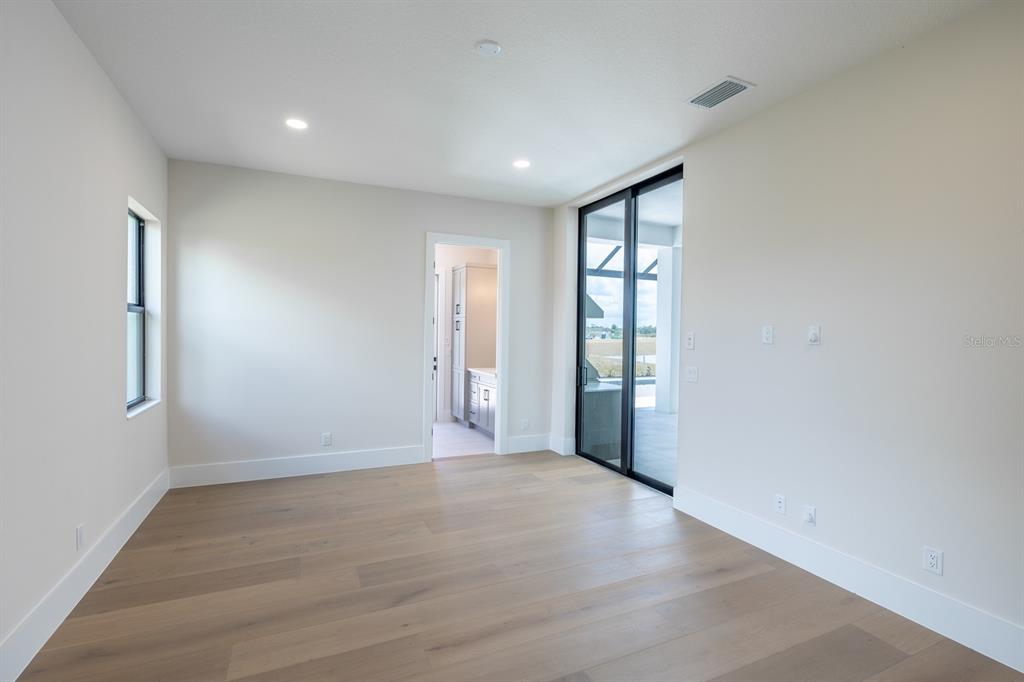 A bright room with light wood floors, recessed lighting, and sliding glass doors to a patio — 1003 BLUE SHELL LOOP, SARASOTA, FL