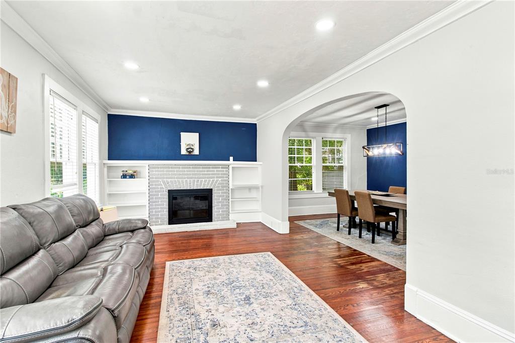 A living room with a fireplace and built-in shelves connects to a dining room — 208 W 17TH STREET, SANFORD, FL