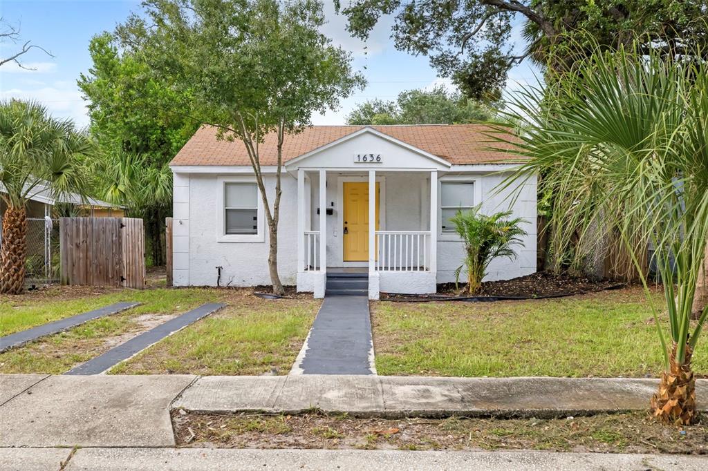 A small, white, single-story house with a yellow front door and a covered porch — 1636 PRESCOTT STREET S, ST PETERSBURG, FL
