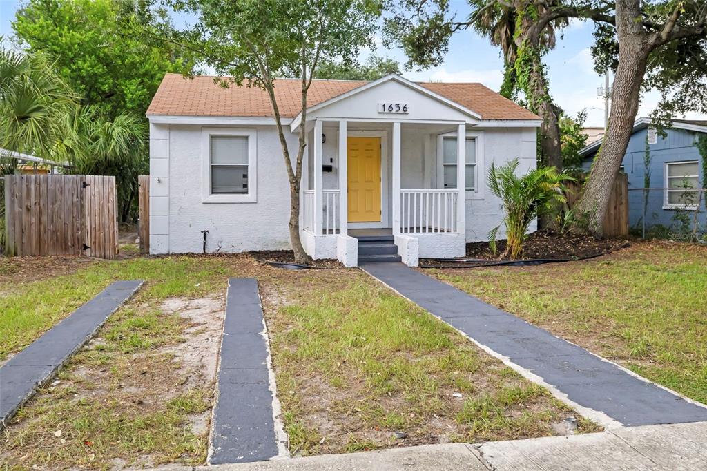 A small white house with a yellow front door and a concrete driveway strip — 1636 PRESCOTT STREET S, ST PETERSBURG, FL