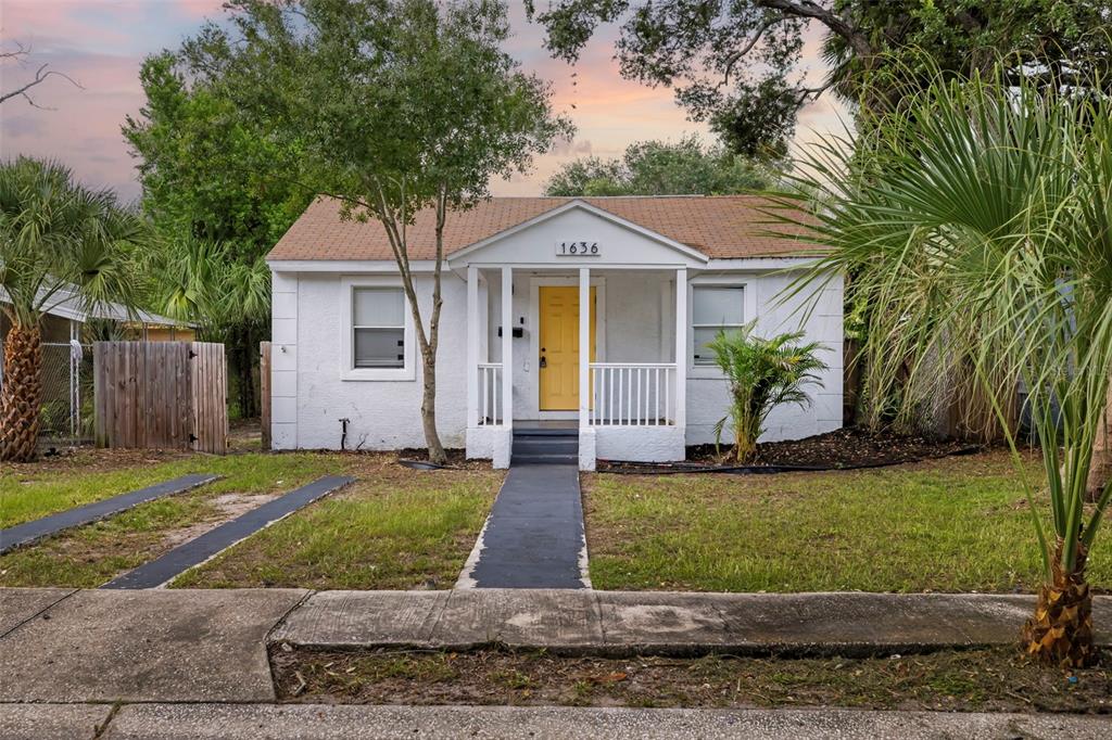A small, white, single-story house with a yellow front door and a covered porch — 1636 PRESCOTT STREET S, ST PETERSBURG, FL