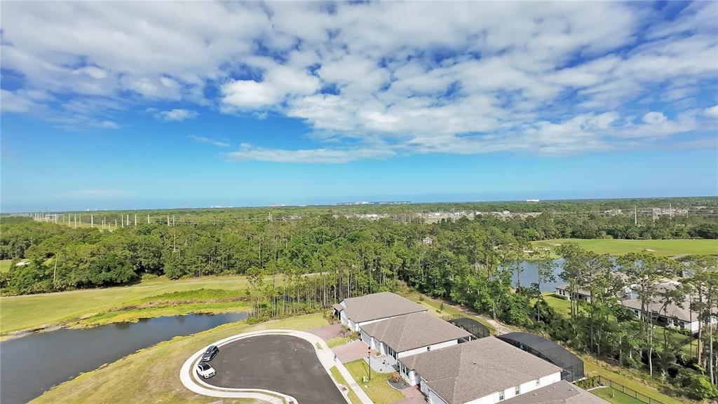 An aerial view shows a suburban neighborhood with houses, a pond, and a golf course — 3160 FIRETHORN CIRCLE, DAYTONA BEACH, FL