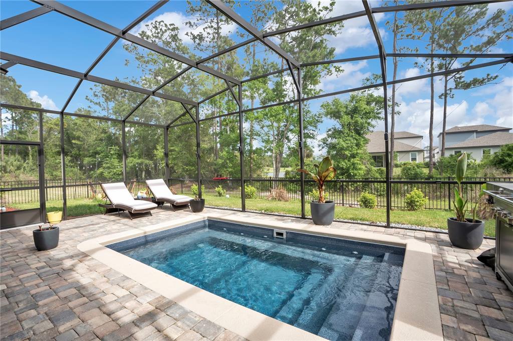A small rectangular pool sits on a paved patio inside a screened-in pool enclosure — 3160 FIRETHORN CIRCLE, DAYTONA BEACH, FL