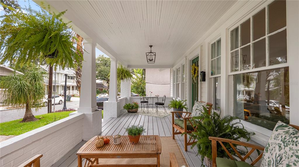 A covered front porch features white columns, a wooden coffee table, and several potted plants — 730 COLLEGE AVENUE, LAKELAND, FL
