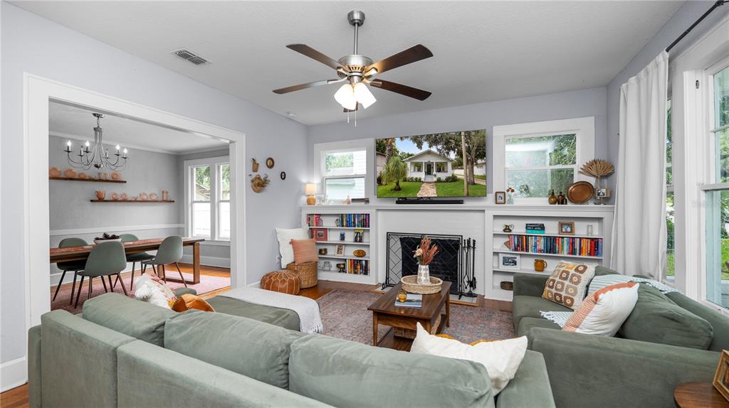 A living room with a fireplace, built-in bookshelves, a green sectional sofa, and a ceiling fan — 730 COLLEGE AVENUE, LAKELAND, FL
