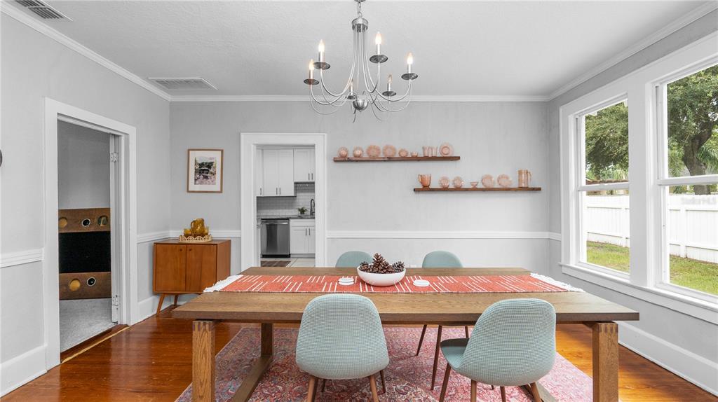 A dining room features a wooden table, light blue chairs, a chandelier, and two wall shelves — 730 COLLEGE AVENUE, LAKELAND, FL
