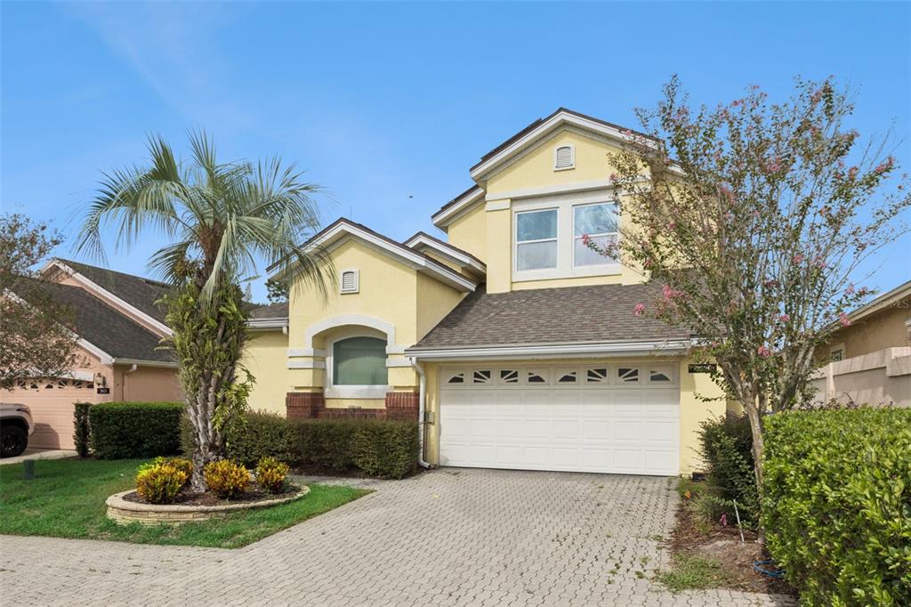 A two-story yellow house with a two-car garage, a palm tree, and a paved driveway — 2619 WINDCHIME COURT, ORLANDO, FL