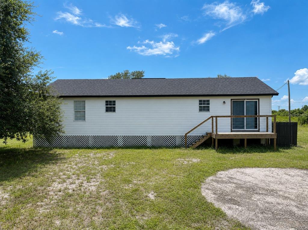 The exterior of a white house features a wooden deck and lattice skirting — 1416 WELLS AVENUE, LEHIGH ACRES, FL