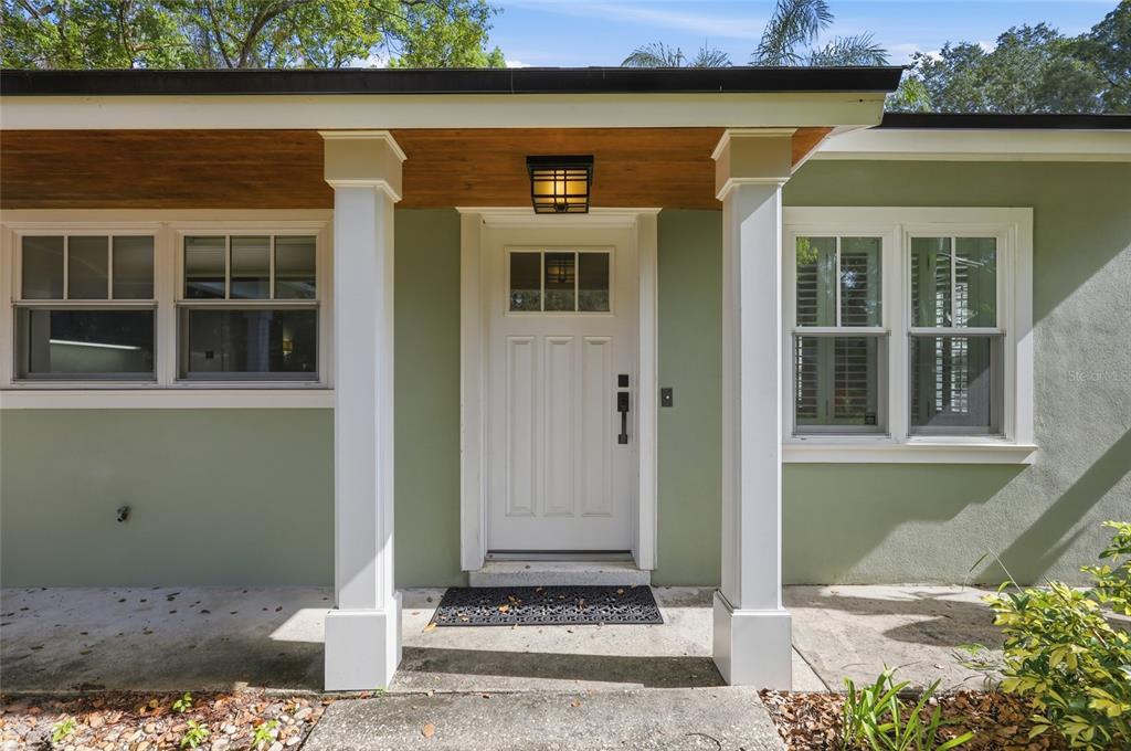 A white front door with a glass pane is centered under a covered porch entryway — 1431 PALM AVENUE, WINTER PARK, FL