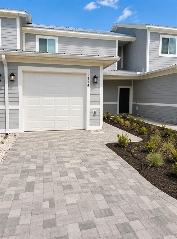 A light blue two-story townhouse with a single-car garage and a gray paver driveway — 2414 WILLOW WAY, WINTER HAVEN, FL