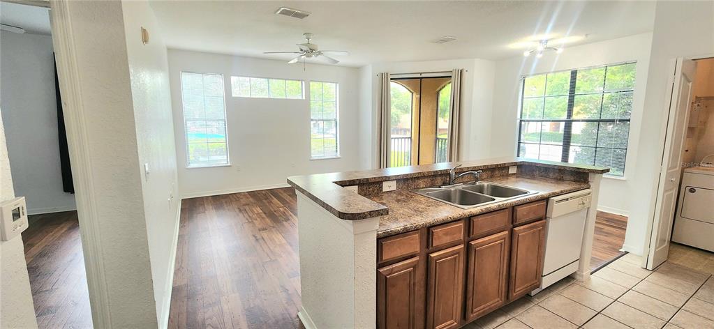 A kitchen with a breakfast bar and sink overlooks a living area with wood flooring — 6171 METROWEST BOULEVARD UNIT 107, ORLANDO, FL