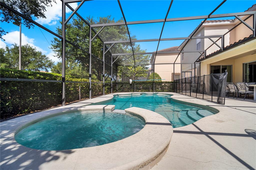 A swimming pool and attached hot tub are enclosed within a screened-in patio area — 4007 OAKRISE LOOP, DAVENPORT, FL