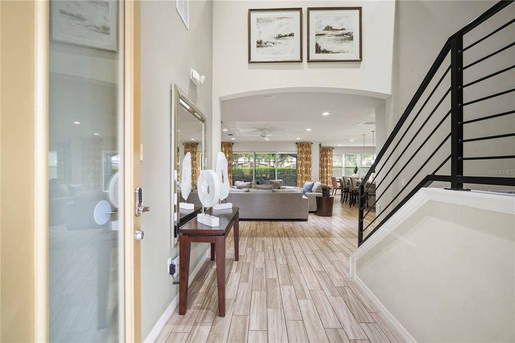 A foyer with wood-look tile flooring leads into an open-concept living and dining area — 4007 OAKRISE LOOP, DAVENPORT, FL