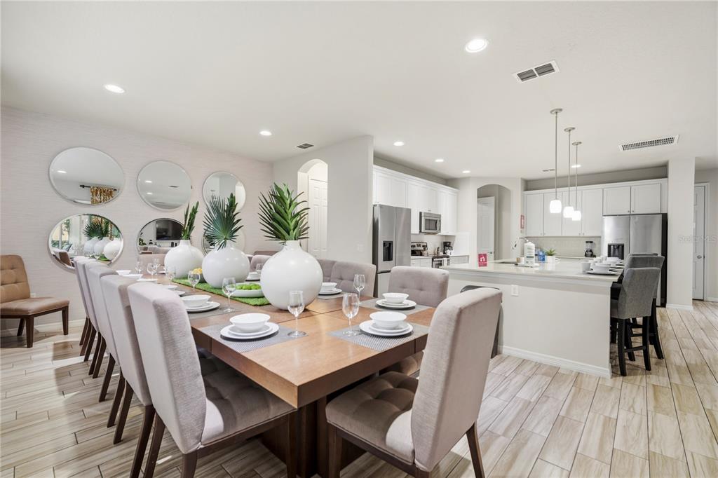 A dining area with a long wooden table and chairs adjacent to an open kitchen — 4007 OAKRISE LOOP, DAVENPORT, FL