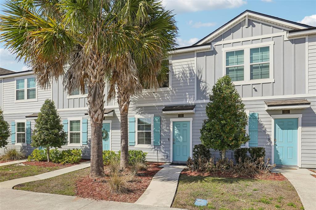 A row of gray townhouses features light blue front doors, shutters, and palm trees — 70 WHISPERING BROOK DRIVE, ST AUGUSTINE, FL