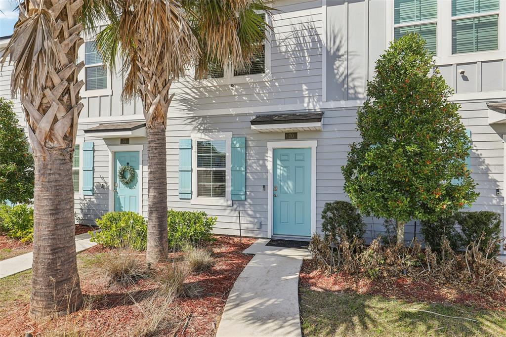 A two-story townhouse exterior features light gray siding, light blue doors, and palm trees — 70 WHISPERING BROOK DRIVE, ST AUGUSTINE, FL