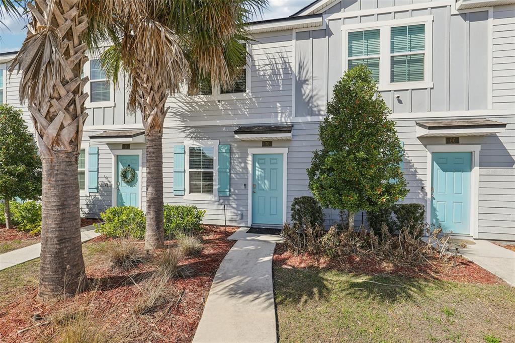 The exterior of a multi-unit townhouse building features light blue doors and gray siding — 70 WHISPERING BROOK DRIVE, ST AUGUSTINE, FL