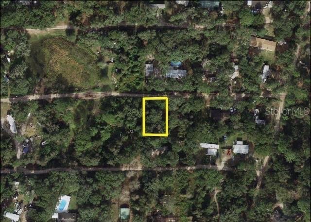 An aerial view shows a rectangular lot outlined in yellow amidst a wooded residential area — 20745 SE 156 TH PLACE, UMATILLA, FL