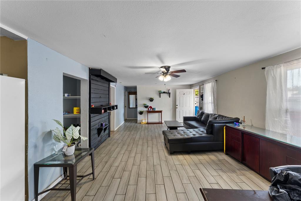 A living room features light wood-look tile flooring, a black accent wall, and a ceiling fan — 5712 15TH STREET E, BRADENTON, FL
