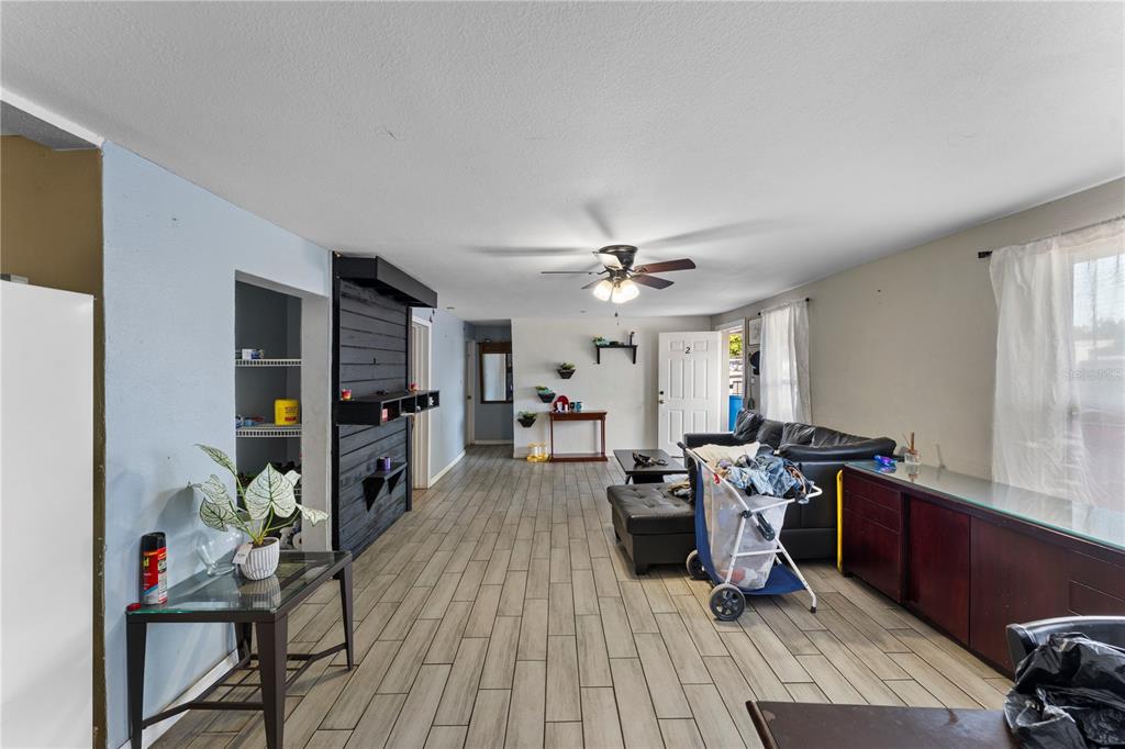 A living room features light wood-look tile flooring, a black accent wall, and a ceiling fan — 5712 15TH STREET E, BRADENTON, FL