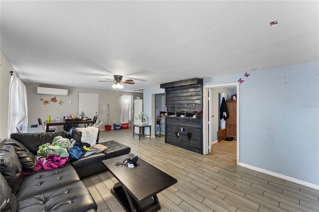 A living room features a black leather sectional, a coffee table, and wood-look tile flooring — 5712 15TH STREET E, BRADENTON, FL