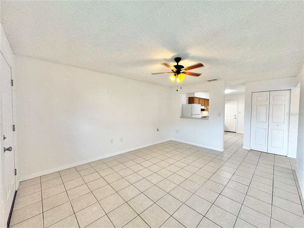 An empty living room features white walls, a ceiling fan, and light-colored tile flooring — 2559 ELM AVENUE, LAKE WALES, FL