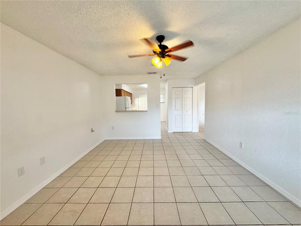 A dining area with beige tile flooring, a ceiling fan, and a kitchen pass-through window — 2559 ELM AVENUE, LAKE WALES, FL