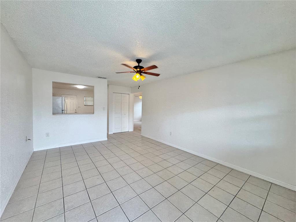 An empty room features white walls, light-colored tile flooring, and a ceiling fan — 2559 ELM AVENUE, LAKE WALES, FL