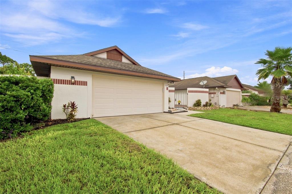 A single-story house with a white stucco exterior, a two-car garage, and a concrete driveway — 7123 SILVERMILL DRIVE, TAMPA, FL