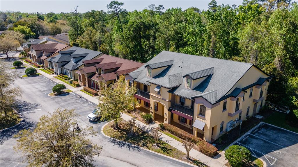 An aerial view shows a multi-story tan apartment building with a gray roof and parking — 1100 TOWN PLAZA COURT UNIT 2010-F, WINTER SPRINGS, FL