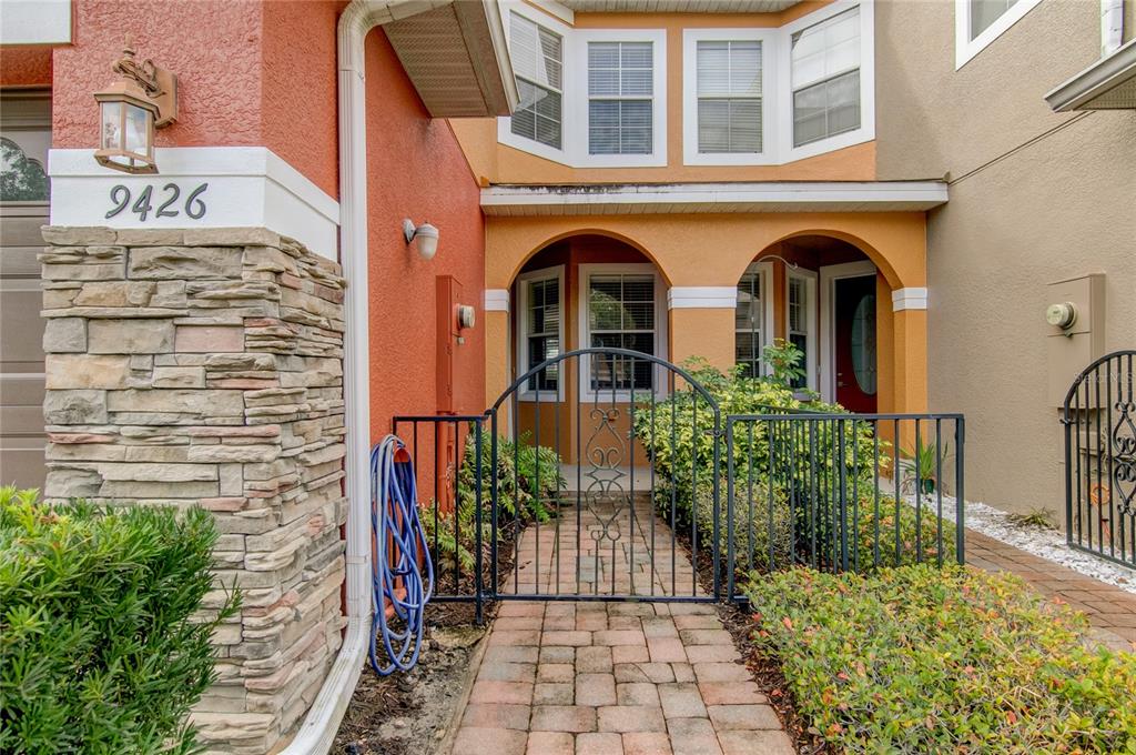 A stone-accented exterior features a gated brick walkway leading to a covered entryway with arches — 9426 SILVER BUTTONWOOD STREET, ORLANDO, FL