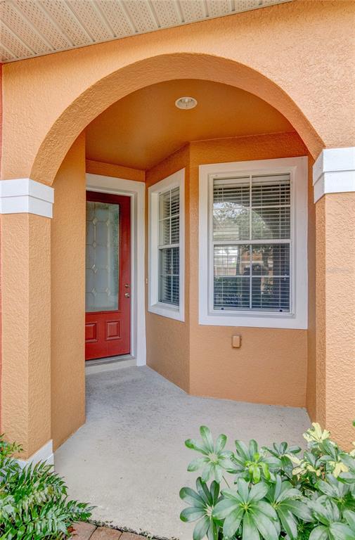 An exterior view of a home entrance featuring a red door under an arched porch — 9426 SILVER BUTTONWOOD STREET, ORLANDO, FL
